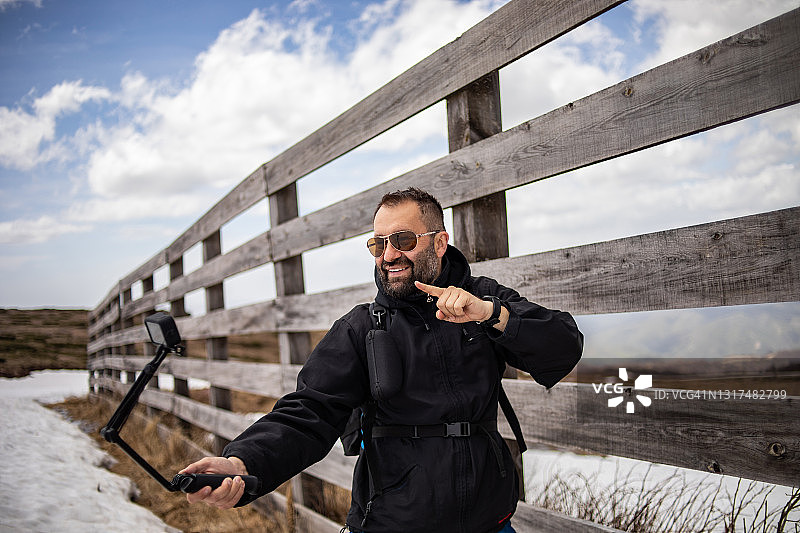 徒步旅行者爬山，用Gopro相机拍摄视频，为他的视频博客制作视频图片素材