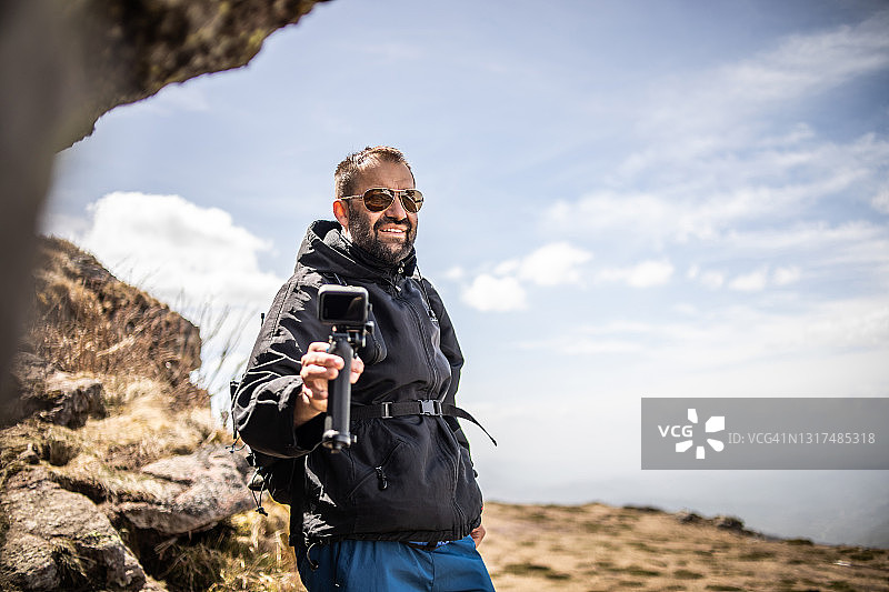 徒步旅行者爬山，用Gopro相机拍摄视频，为他的视频博客制作视频图片素材