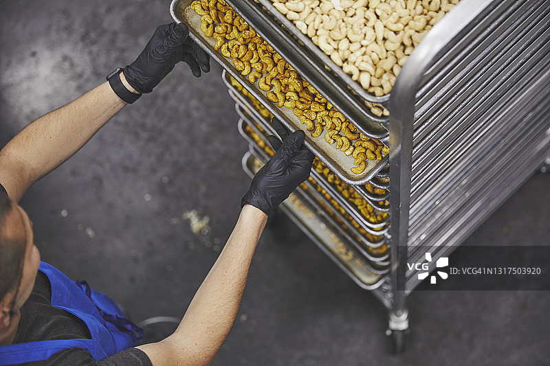 男工人在工厂从架子上取下腰果片图片素材