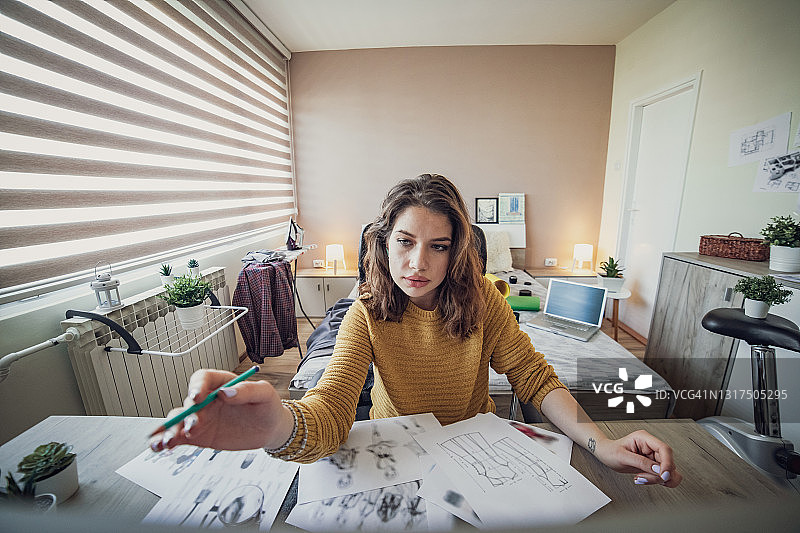 在创意办公室工作的女商人。一位年轻漂亮的女性设计师在家里的房间工作。图片素材