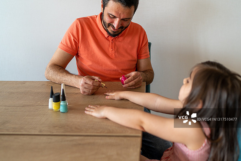 年轻的父亲为女儿涂指甲油图片素材