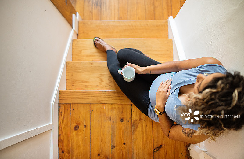 年轻孕妇坐在家里的楼梯上图片素材