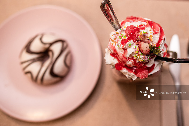 草莓冰沙壶和粉色盘子旁的白色甜甜圈图片素材