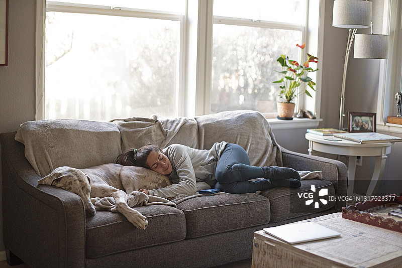 女人躺在沙发上，睡在一条大丹犬身上图片素材