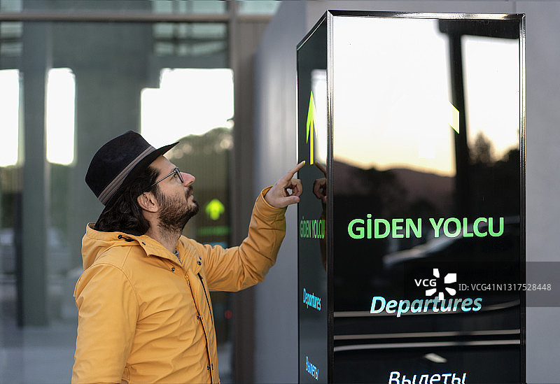 男旅客在机场信息板上查询航班信息图片素材