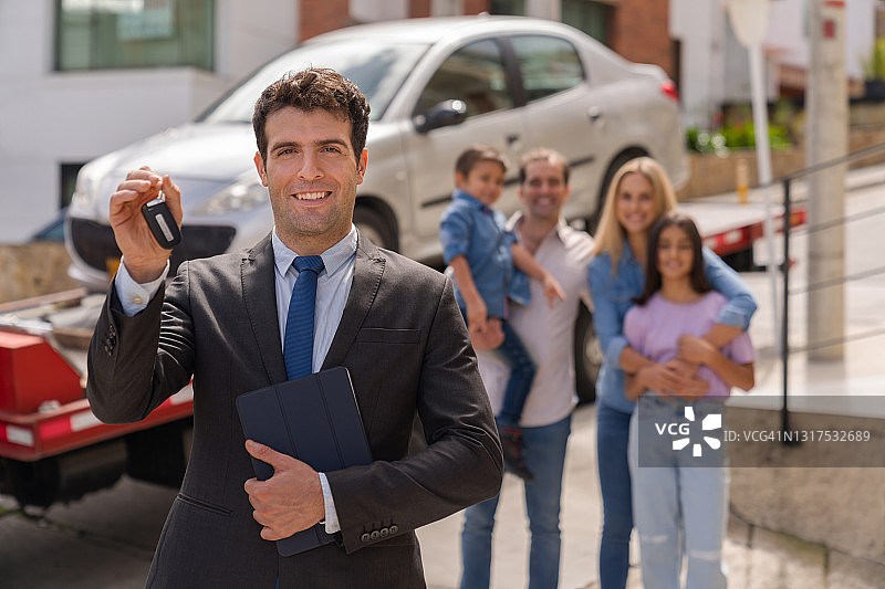 推销员在家向一家人交付汽车并持有钥匙图片素材