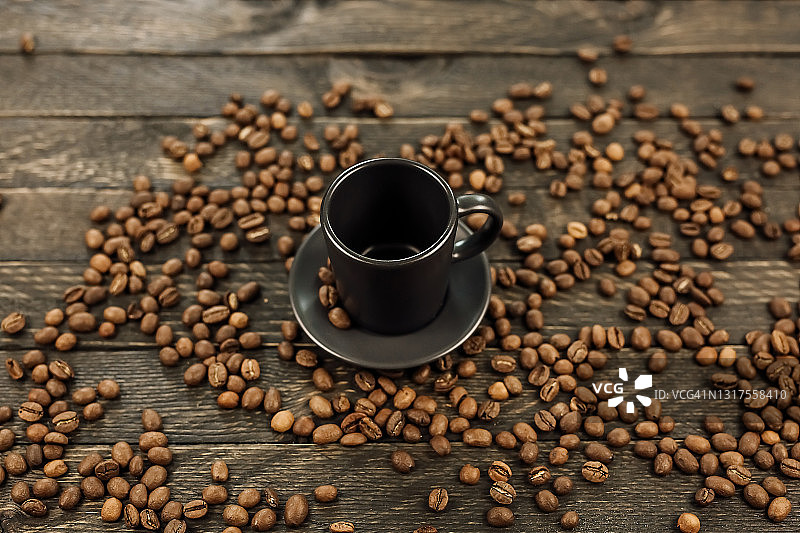 木制背景上的棕色烘焙咖啡豆和一杯咖啡图片素材