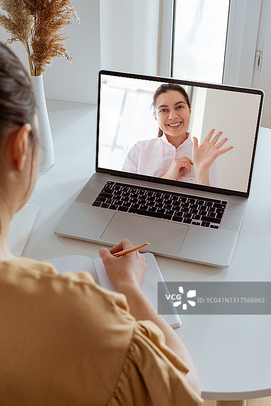 非高加索女性在现代家居室内进行视频通话的背影和特写。不同的工人或朋友在线聊天、网络会议、咨询客户。图片素材