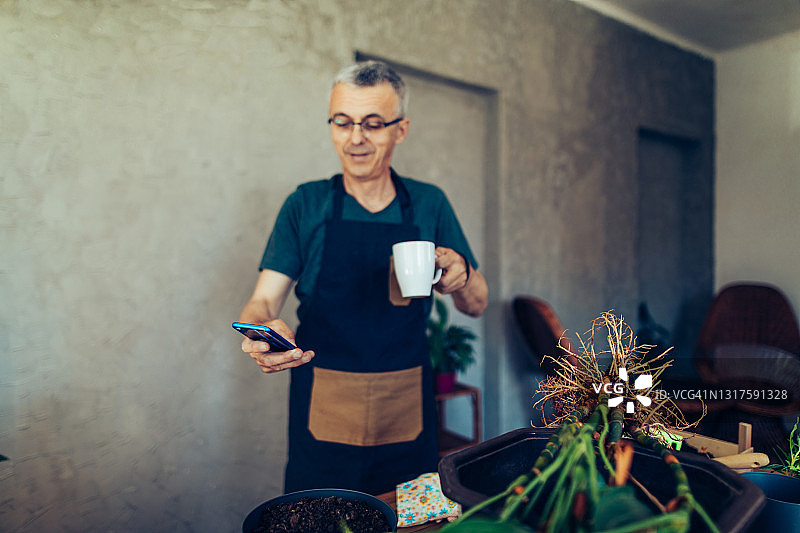 中年花店老板在智能手机上浏览网络图片素材