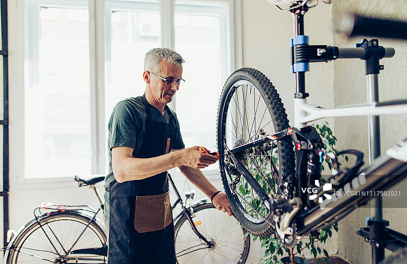 在自行车服务部门兼职的年长修理工图片素材
