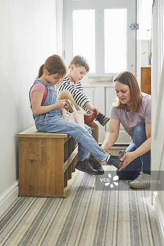 母亲帮助儿童穿鞋准备出门图片素材