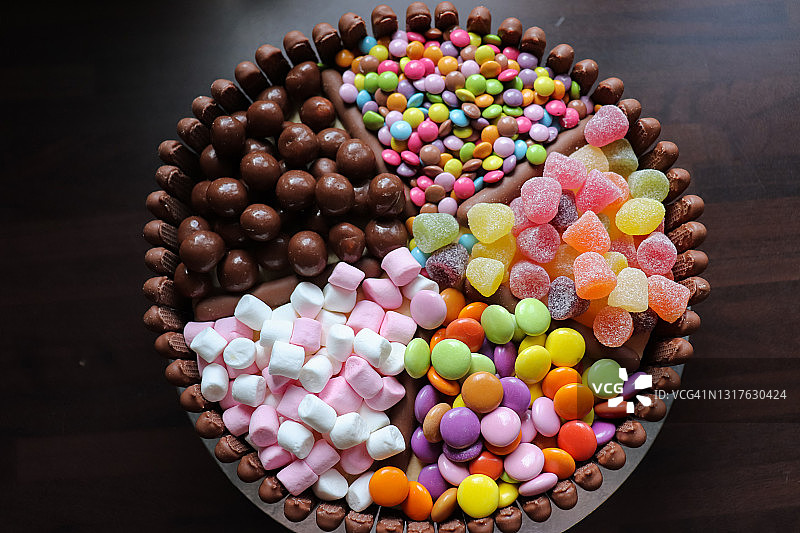 顶部撒满Smarties、棉花糖和其他糖果的巧克力手指饼蛋糕，完整顶视图图片素材