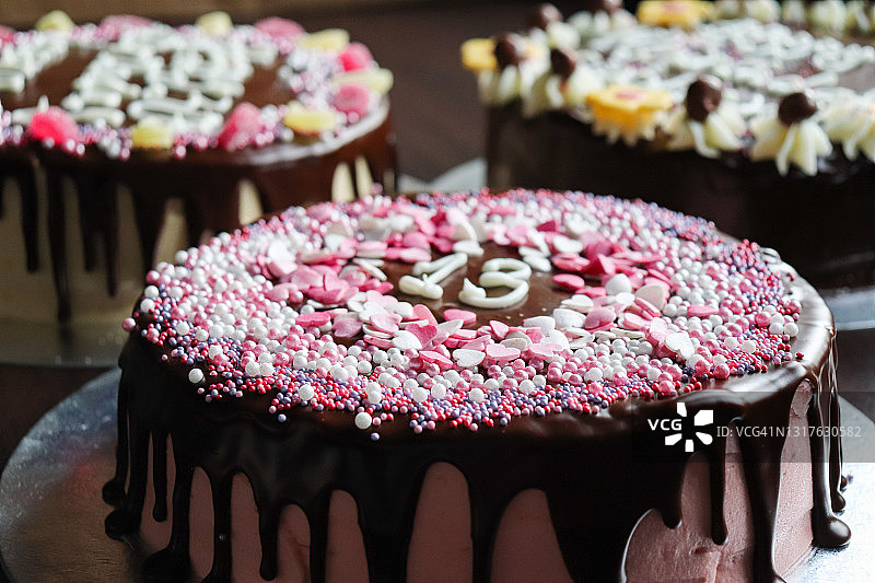 粉色巧克力滴落蛋糕，中间有数字13，装饰着粉色爱心和闪亮糖屑，顶部特写图片素材