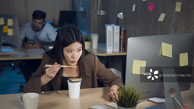 在办公室加班吃方便面的年轻女人图片素材