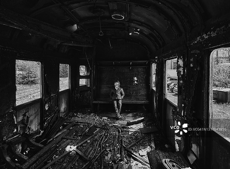 在损毁的火车车厢里戴着面具的男孩图片素材