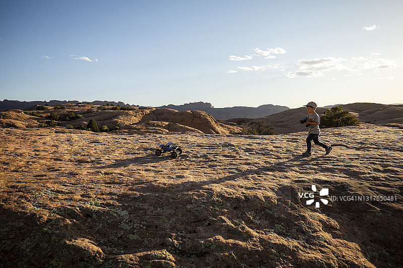 一个男孩在崎岖的地形上驾驶遥控车图片素材