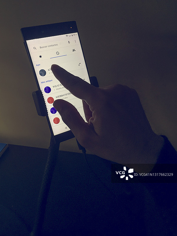 男人在三脚架上使用智能手机的特写图片素材