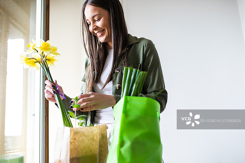 快乐的年轻女人从可重复使用的购物袋中取出食品图片素材