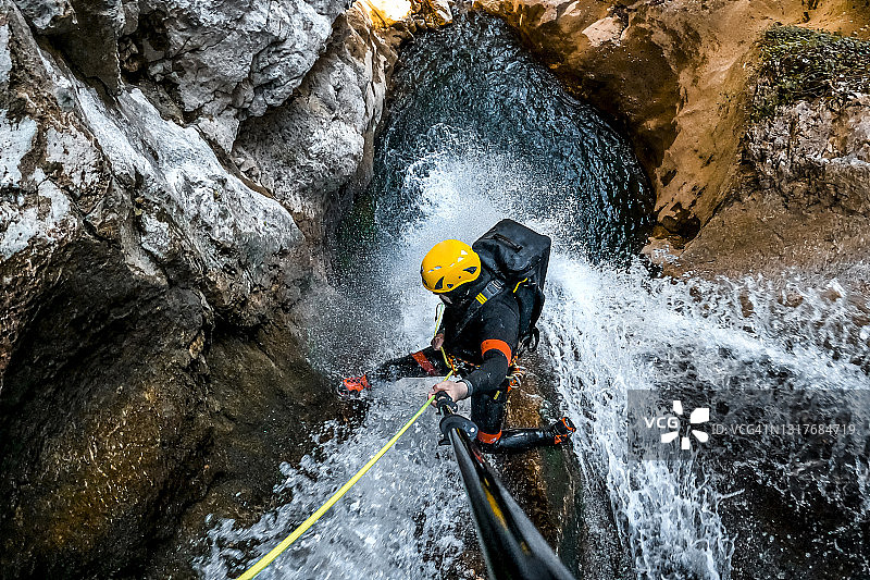 溪降探险者在绳索上滑下瀑布图片素材