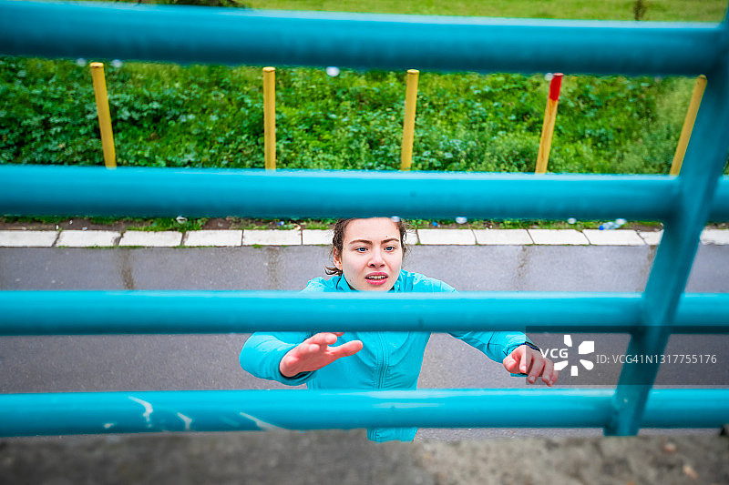 在城市里自由奔跑，举起手臂够金属栏杆的少女图片素材