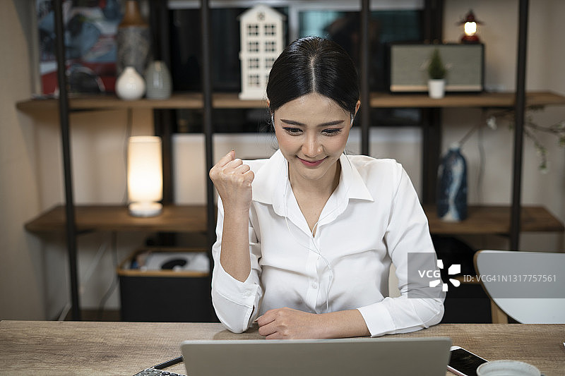 女商人用笔记本电脑在家庭办公室庆祝成功图片素材