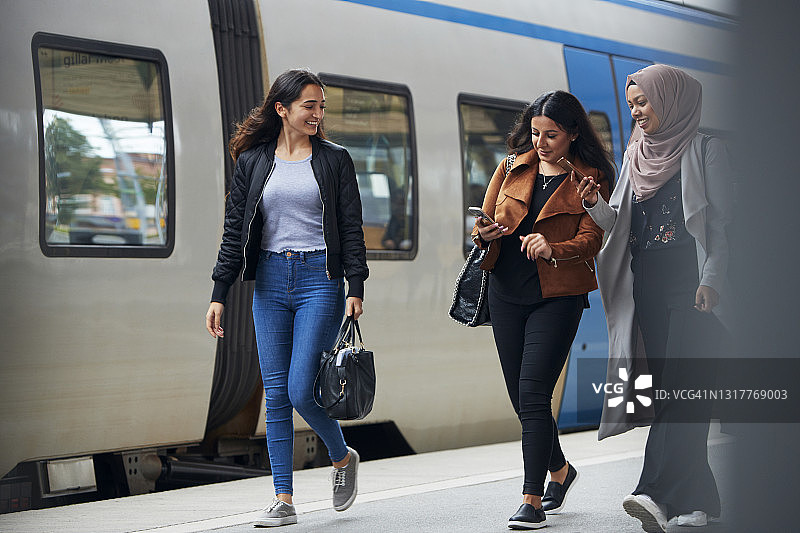 微笑的女性朋友们在火车站站台上图片素材