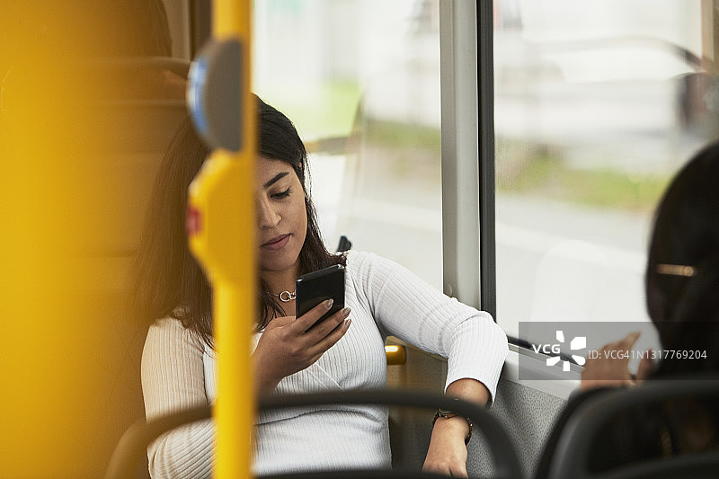 在公交车上使用手机的年轻女子图片素材