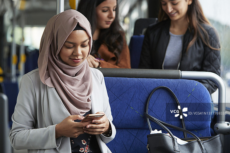 在公交车上使用手机的年轻女子图片素材