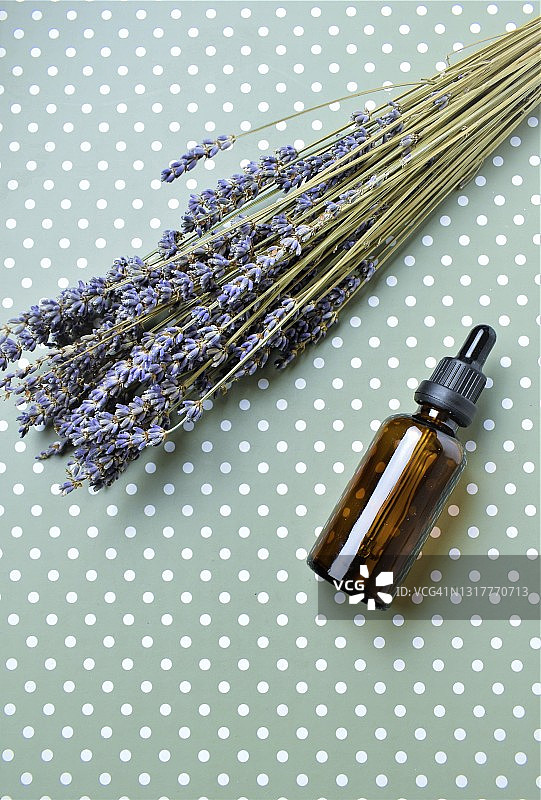 绿底圆点上的精油瓶与薰衣草花束图片素材