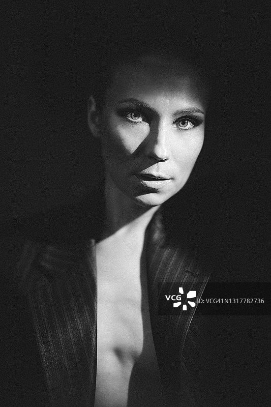 黑白肖像的一个年轻女子穿着一件夹克在一个与烟熏眼睛化妆在一个低调图片素材