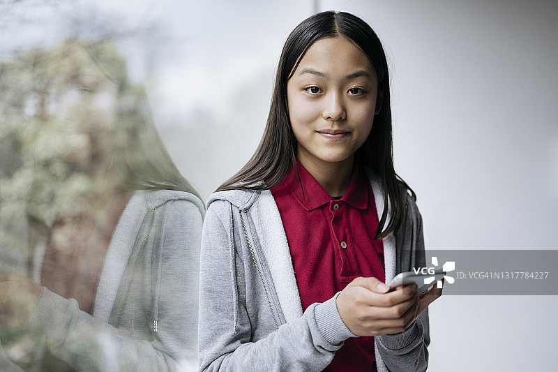 在家使用智能手机的东亚少女肖像图片素材