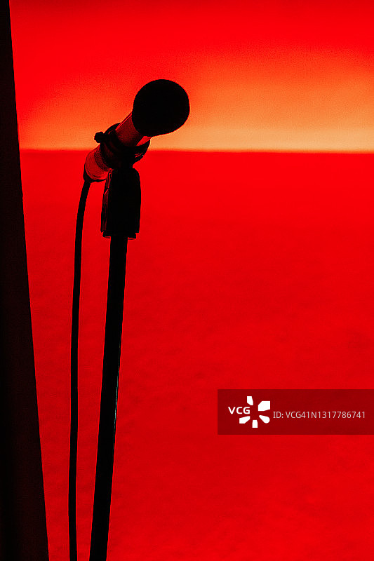 红色灯光下的麦克风剪影图片素材