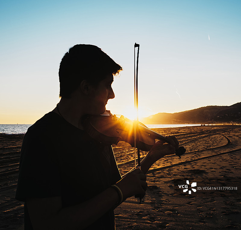 海滩上小提琴家的背光图片素材