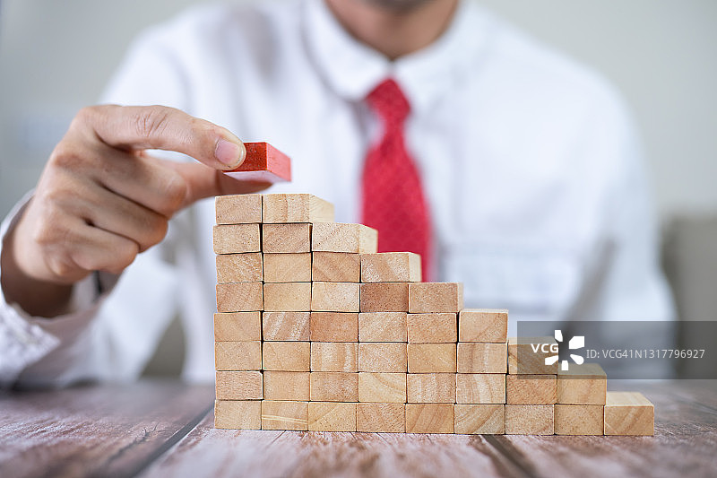 商人在现代办公室抽出或放置木块于塔和半金字塔上，商业中的计划和策略图片素材