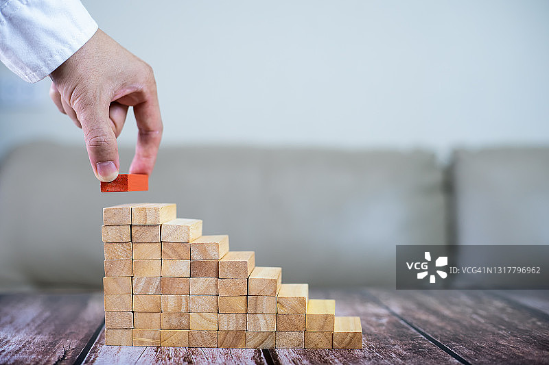 商人在现代办公室抽出或放置木块于塔和半金字塔上，商业中的计划和策略图片素材