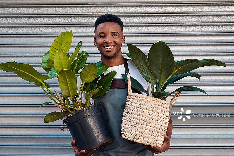 年轻男子在花园中心工作，手捧盆栽的画像图片素材