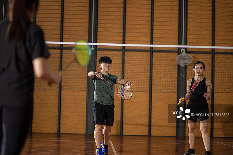 华人女子羽毛球运动员在羽毛球场发球图片素材