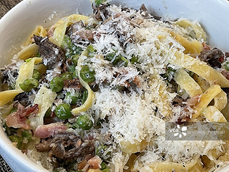 家制意大利宽面，搭配煎猪肉、豌豆、帕尔马干酪和羊肚菌图片素材