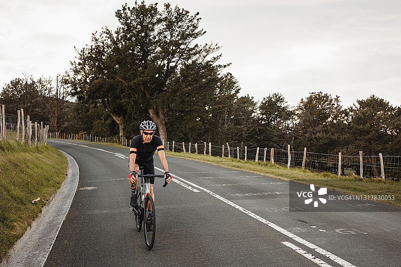 中年男人在山路上练习骑自行车图片素材