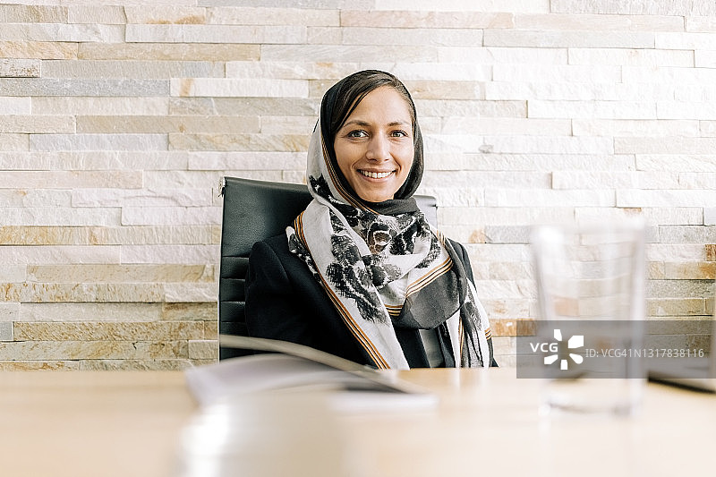 微笑的戴着头巾的女商人坐在会议室里图片素材