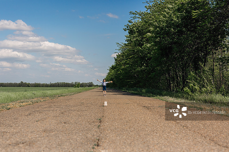 男孩沿着带有分隔带的沥青路奔跑图片素材