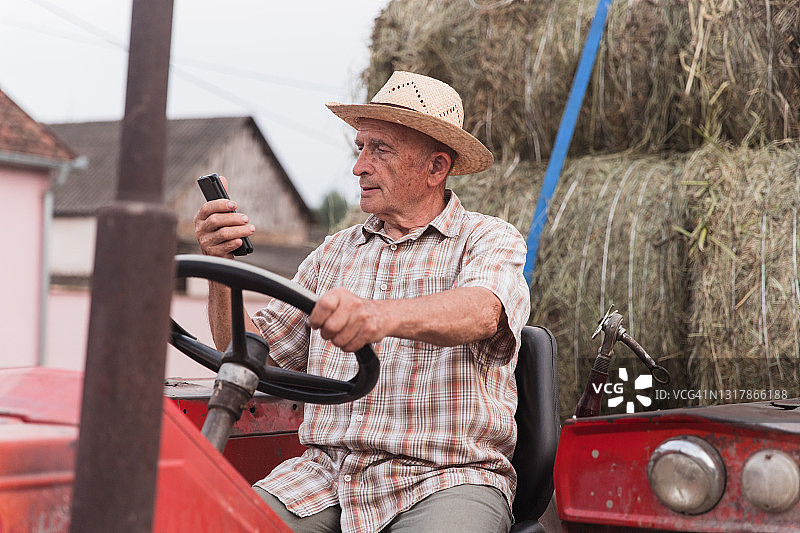 老人坐在拖拉机上与家人进行视频通话图片素材