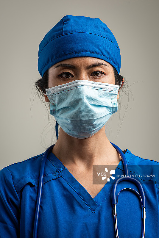 戴着防护口罩，看着镜头的严肃亚洲中年医疗保健工作者图片素材
