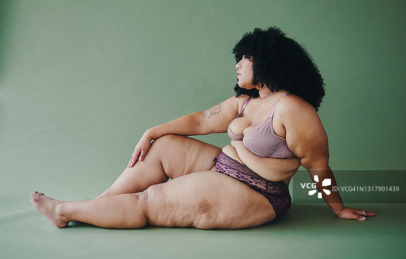 年轻性感女人在绿色背景影棚里穿内衣摆姿势全身照图片素材