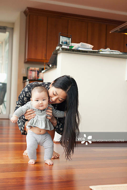 母亲扶着女婴学走路图片素材