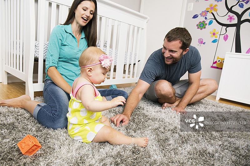 中年夫妇在育儿室地毯上和女儿玩耍图片素材