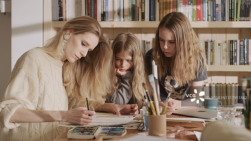 工作中的时装设计师妈妈。与小女儿一起绘制时装草图图片素材