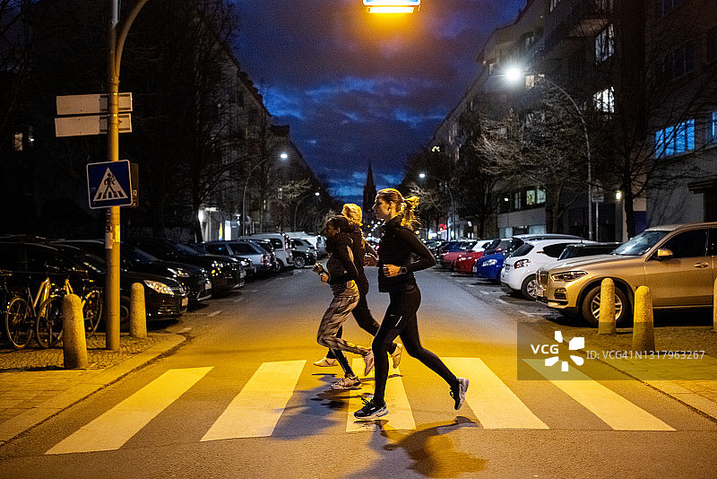 夜间城市街道上一起慢跑的城市跑步者图片素材