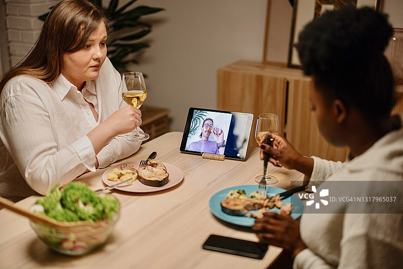 深夜，朋友们通过视频通话与共同的朋友共进晚餐图片素材
