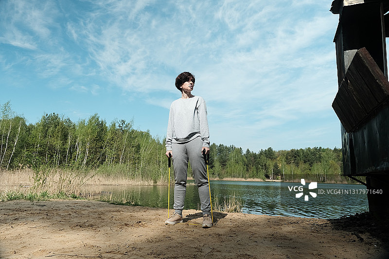 中年妇女在湖岸边用阻力带锻炼图片素材